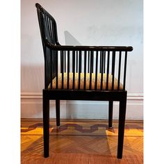 a wooden chair sitting on top of a hard wood floor next to a white wall