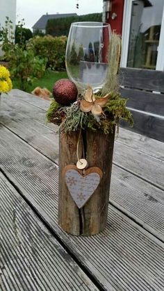 a wine glass sitting on top of a wooden table next to a vase filled with flowers