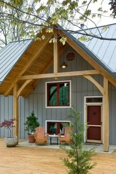 a small house with a porch and covered in wood shingles, sitting on a wooden deck