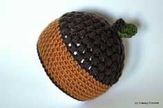 a crocheted hat with a green leaf on the top and brown, white, and black trim