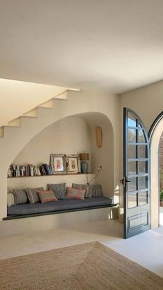 a living room filled with furniture next to an open door and stairs leading up to the second floor