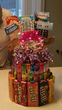 a woman sitting in front of a cake made out of candy bars and candies