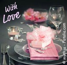 a table set with pink napkins, silverware and wine glasses for valentine's day