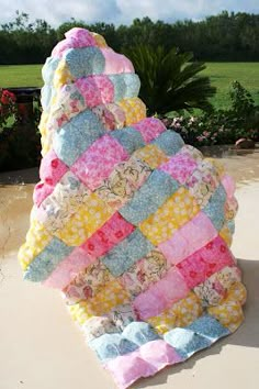 a quilted blanket sitting on top of a table next to a flower pot filled with flowers