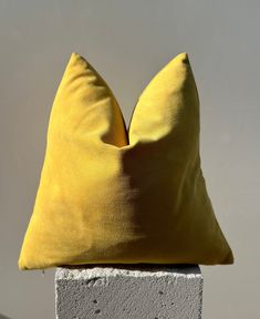 a yellow pillow sitting on top of a cement block