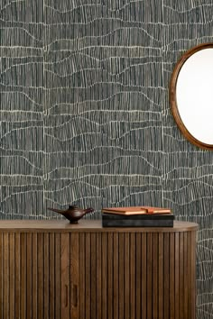 a wooden cabinet sitting in front of a mirror on top of a wall next to a table