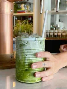 a person holding a green drink with ice in it