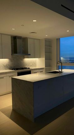 a kitchen with an island in front of a large window overlooking the city at night