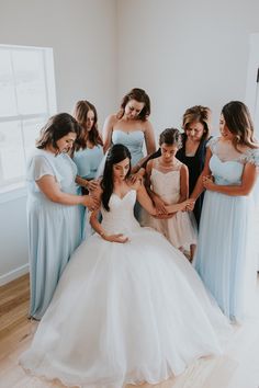 a group of women standing next to each other in front of a white wall wearing dresses