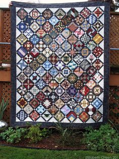 a quilt hanging on the side of a fence