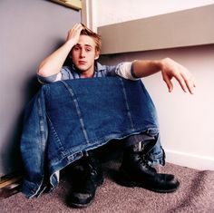 a young man sitting on the floor with his jeans over his face and hands behind his head