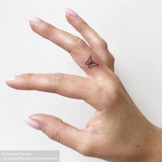 a person's hand with a small butterfly tattoo on the middle of their finger