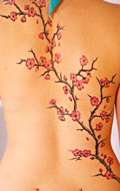 the back of a woman's body with cherry blossom tattoos on her lower back