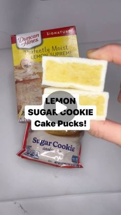 lemon sugar cookie cake packs are being held by someone's hand over the counter