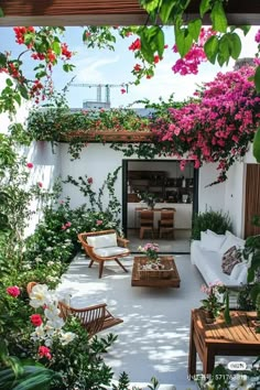 an outdoor living area with wicker furniture and pink flowers on the wall, surrounded by greenery