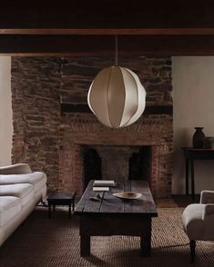 a living room filled with furniture and a fire place in front of a stone wall