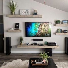 a flat screen tv sitting on top of a wooden shelf next to a black couch