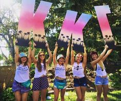 four girls holding up signs that say ky and palm trees in front of their faces