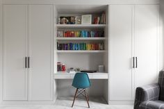 a chair sitting in front of a white book shelf filled with lots of books next to a window