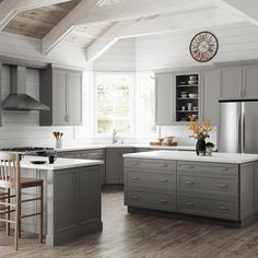 a kitchen with gray cabinets and white counter tops, an island in front of the stove