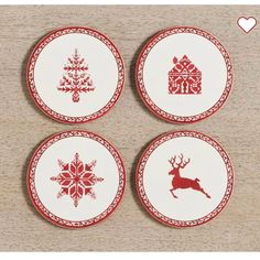 four red and white plates with christmas designs on them sitting on a wooden table top