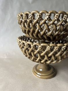 two decorative bowls with skulls in them on a white tableclothed surface, one is gold and the other is brown