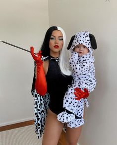 a woman holding a baby dressed in dalmatian costumes