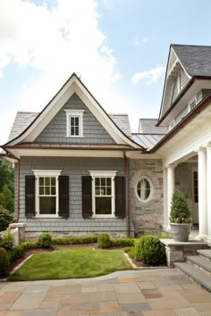 the exterior of a gray house with black shutters and white trim on the windows