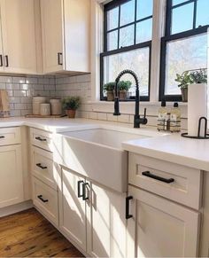 a kitchen with white cabinets and black handles on the windowsills is seen in this image