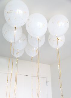 several white balloons are hanging from the ceiling