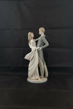 a figurine of two people standing next to each other on a black background