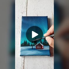 someone is painting a christmas scene on a canvas with a video playing button in the middle