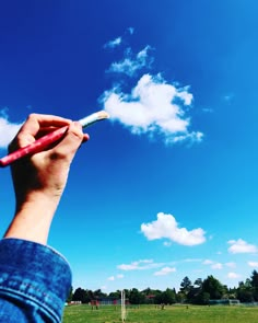 a person is holding a red and white object in their hand while flying a kite