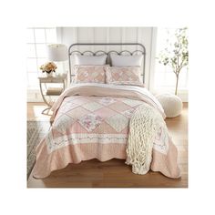 a bed with pink and white bedspread, pillows and blankets on top of it