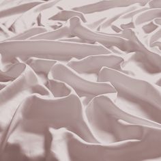 an unmade bed covered in white sheets and comforters, with the top sheet pulled down