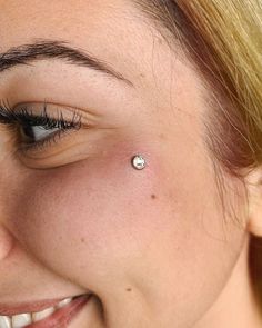 a close up of a woman's eye with a piercing on her forehead and nose