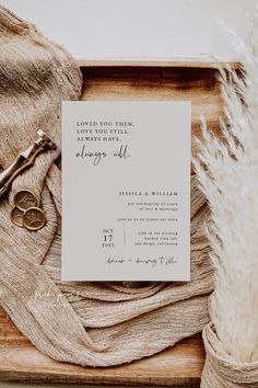 the wedding stationery is laid out on a wooden tray with two pairs of scissors