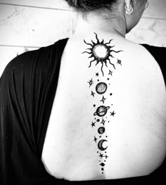 the back of a woman's shoulder with stars and planets on her left side