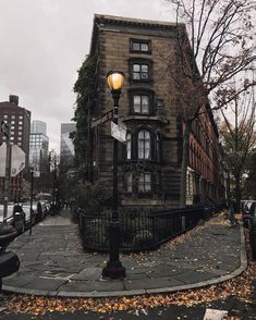 an old brick building on the corner of a street with a lamp post in front of it