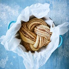 some kind of bread wrapped in paper on a blue tablecloth with white waxing