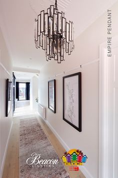 a long hallway with chandelier and pictures on the wall in front of it