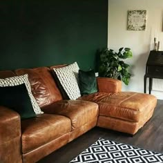 a brown leather couch sitting on top of a wooden floor next to a black and white rug