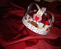 a red and white hat with hearts on it sitting on top of a red cloth