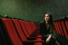 a woman is sitting in an empty theater