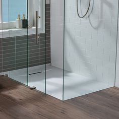 a bathroom with a walk in shower next to a bathtub and wooden flooring