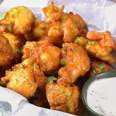 a basket filled with fried food next to a bowl of ranch dressing