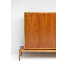 a wooden cabinet sitting on top of a white floor next to a shelf with two doors