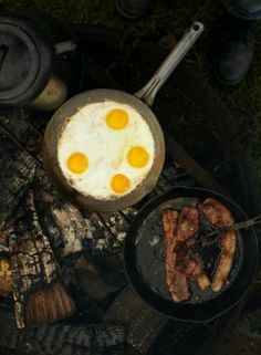 eggs and sausages are cooking on an open fire