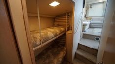 a bunk bed sitting in the corner of a room next to a stair case and toilet