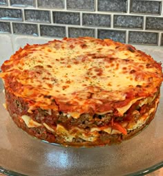 a pizza sitting on top of a glass platter covered in cheese and sauces